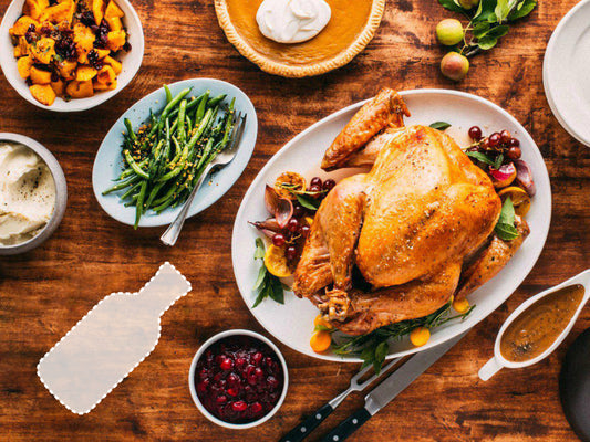 A full table of turkey, gravy, mashed potatoes, green beans, stuffing, pumpkin pie, cranberries, with the outline of a missing bottle of McMasters' Hawg Sauce